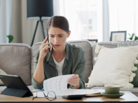 Mulher falando no telefone enquanto segura papéis, simbolizando ansiedade financeira.