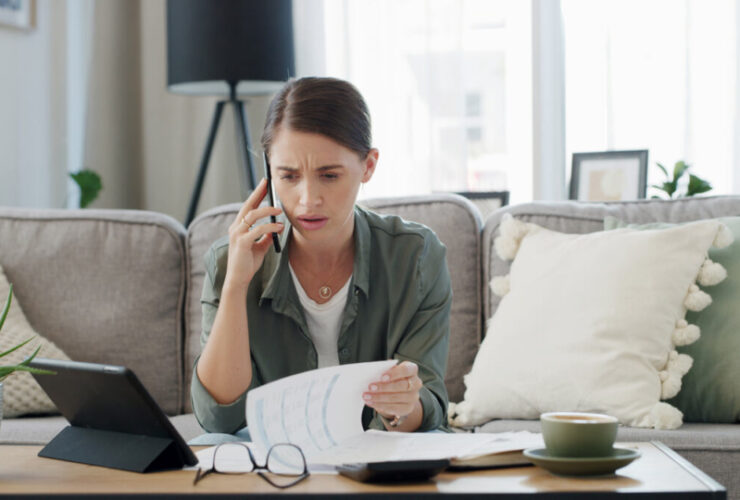Mulher falando no telefone enquanto segura papéis, simbolizando ansiedade financeira.