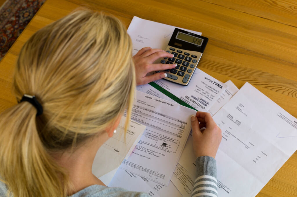 Ferramentas para controlar gastos: como unir inteligência artificial e apps financeiros para economizar de verdade 2 Mulher analisando contas e usando calculadora como ferramenta para controlar gastos.
