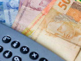 Notas de dinheiro ao lado de calculadora, representando o cálculo do décimo terceiro salário.