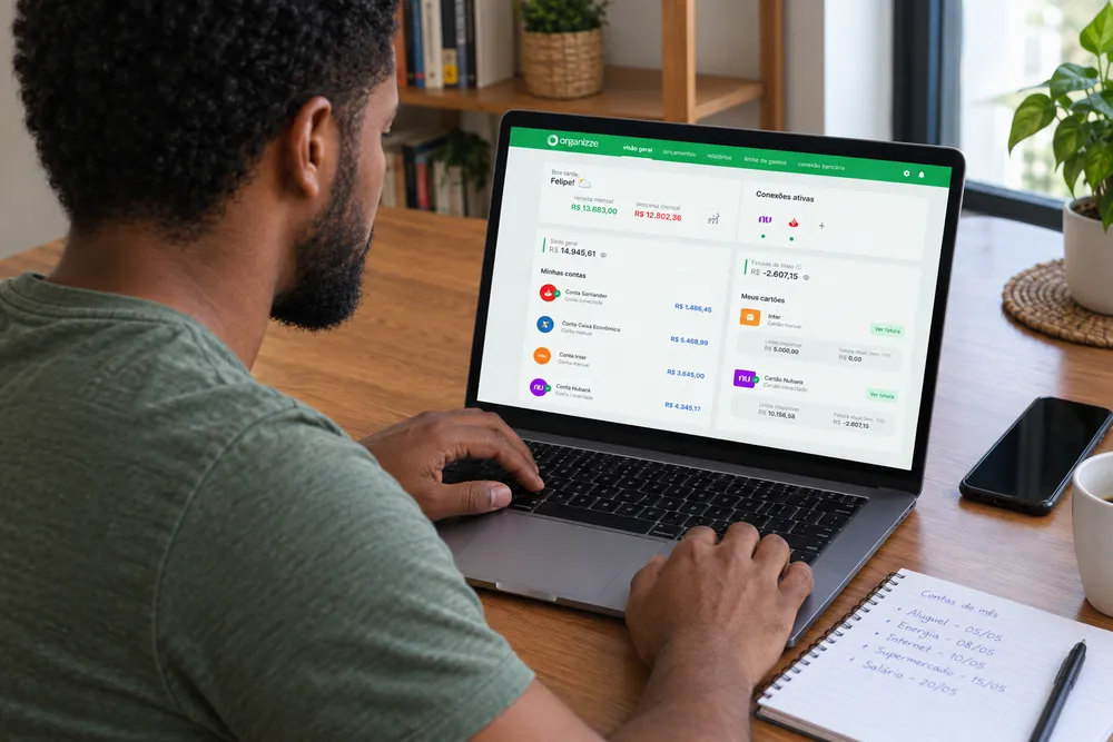 Homem organiza contas no notebook com apoio de calendário financeiro da Organizze.