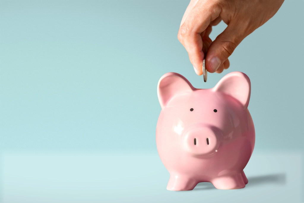 Inteligência financeira: o que é, benefícios e como desenvolver a habilidade 2 pessoa adicionando moeda em porquinho, representando a inteligência financeira