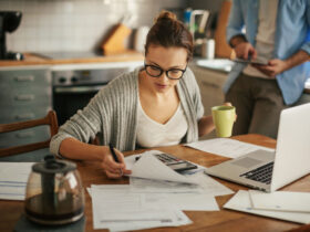 Mulher usando notebook e calculadora para saber como dividir o salário do mês.