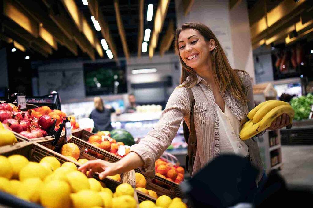 Mulher fazendo compras depois de aprender como economizar no supermercado.