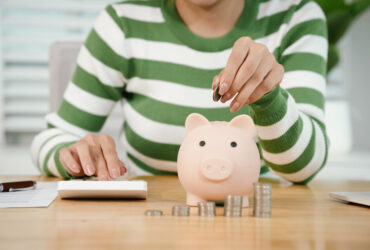 Pessoa calculando finanças pessoais e guardando dinheiro no cofrinho depois de entender como funciona aposentadoria privada na prática.