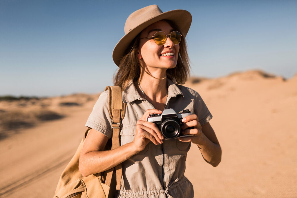 Como juntar dinheiro para viajar? Guia fácil e completo para se preparar 2 mulher com câmera tirando fotos de seu destino nas férias depois de saber como juntar dinheiro para viajar