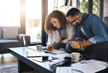 casal anotando finanças e pesquisando no notebook como organizar as contas da casa