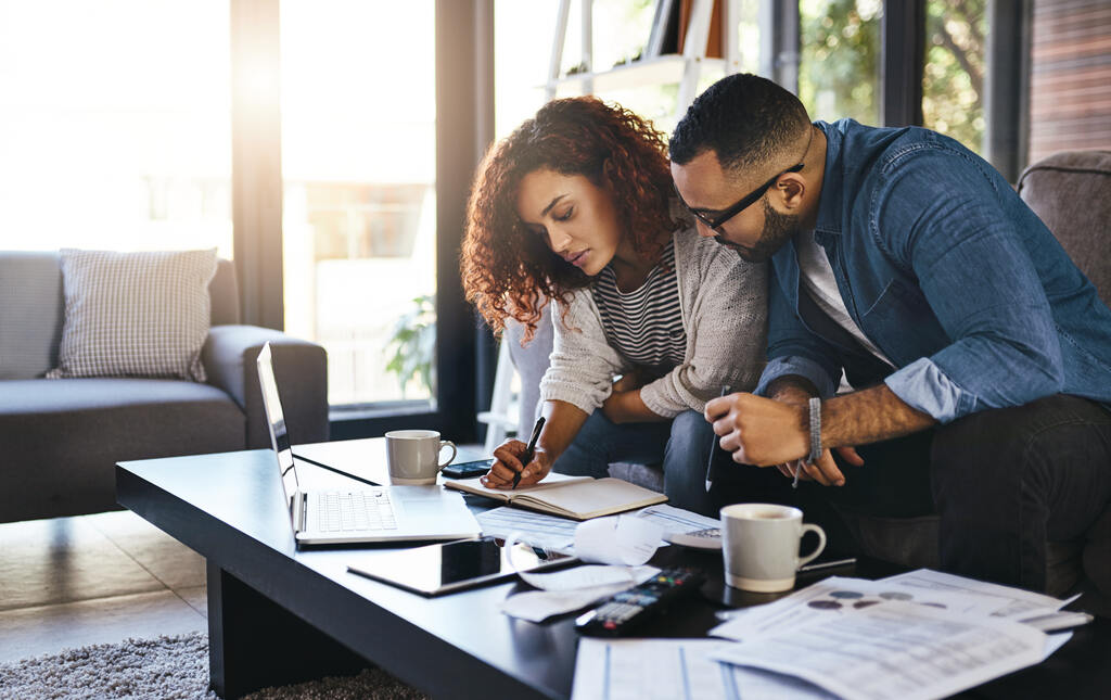 casal anotando finanças e pesquisando no notebook como organizar as contas da casa