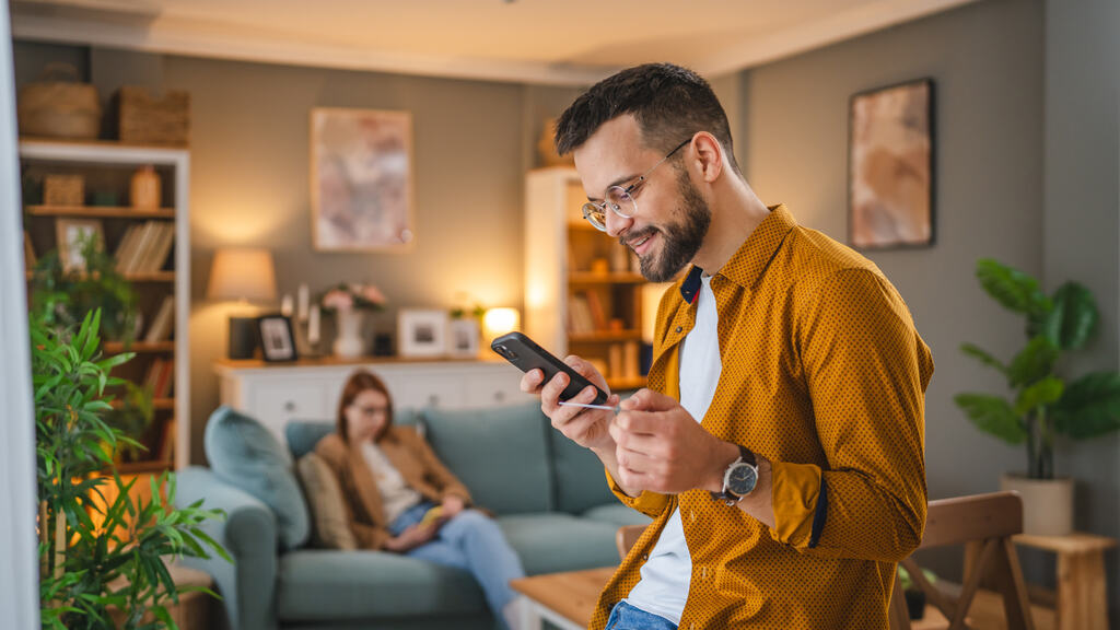 homem pesquisando no celular sobre como parar de gastar por impulso