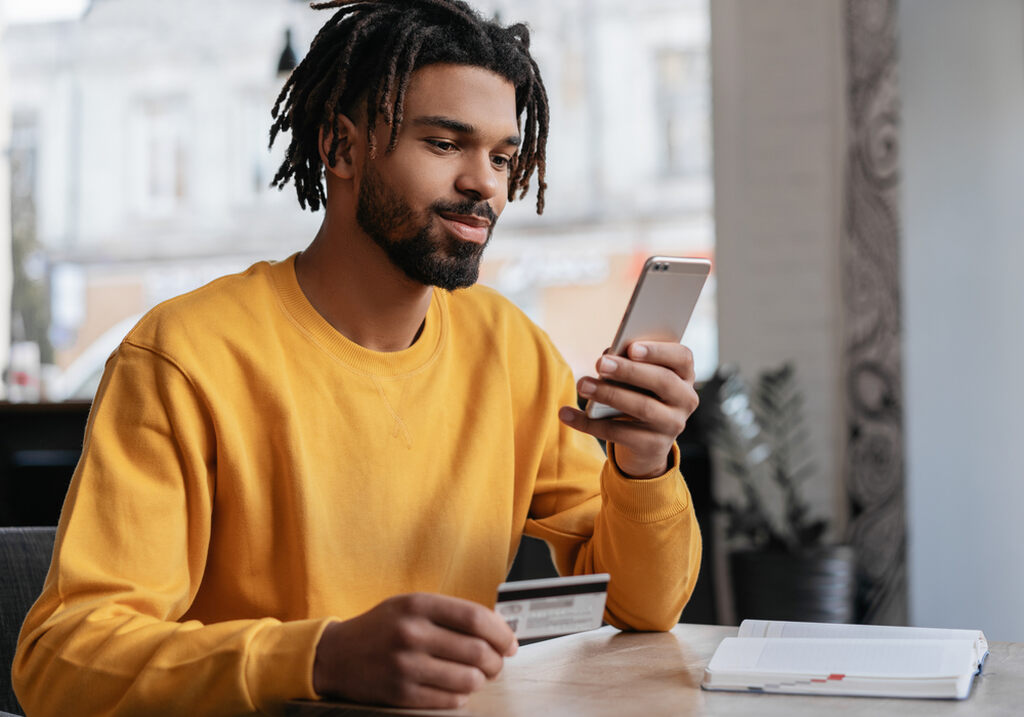 Consumo consciente: como mudar seus hábitos e melhorar suas finanças 3 homem usando app de finanças no celular para incentivar o consumo consciente