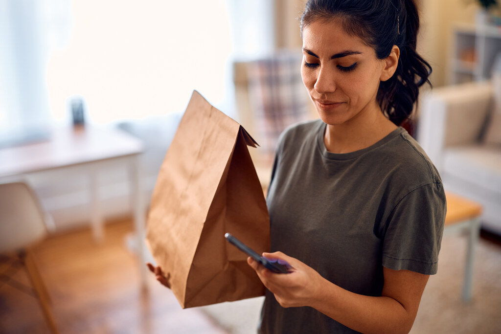 Consumo consciente: como mudar seus hábitos e melhorar suas finanças 2 mulher segurando encomenda representando o consumo consciente