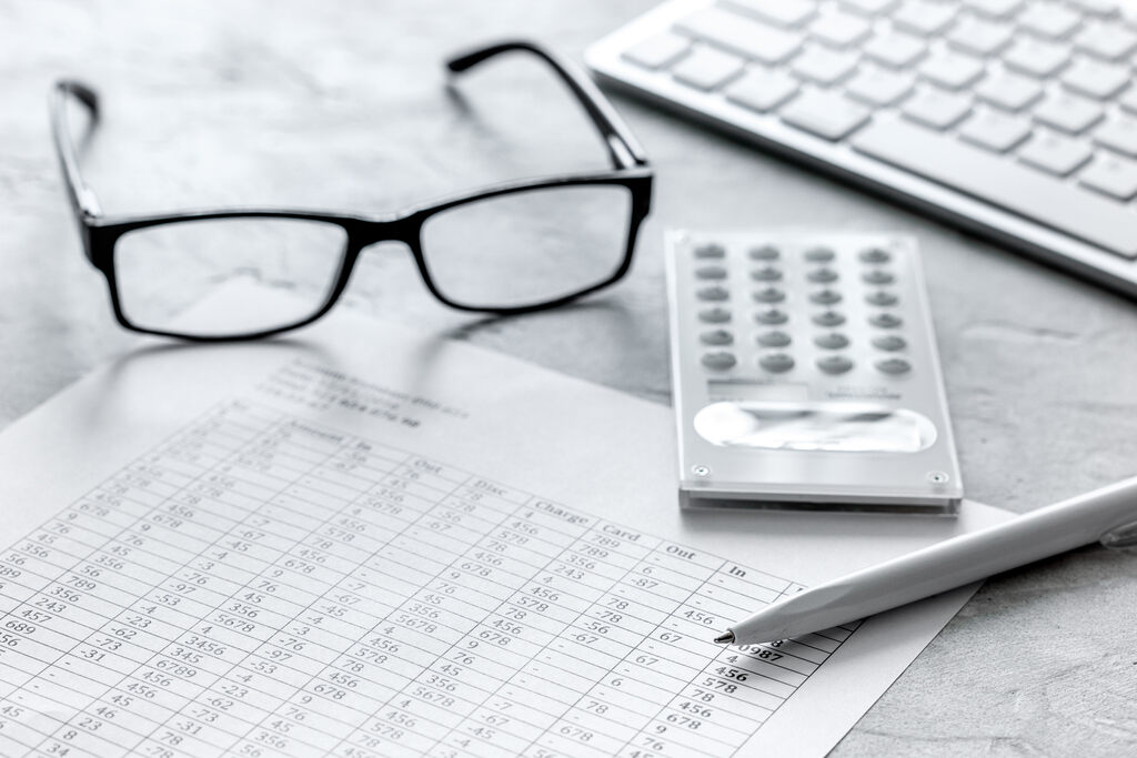 Declaração anual do MEI (DASN-SIMEI): tudo o que você precisa saber 2 mesa de escritório com calculadora, caneta, papel e óculos representando a entrega da declaração anual do MEI