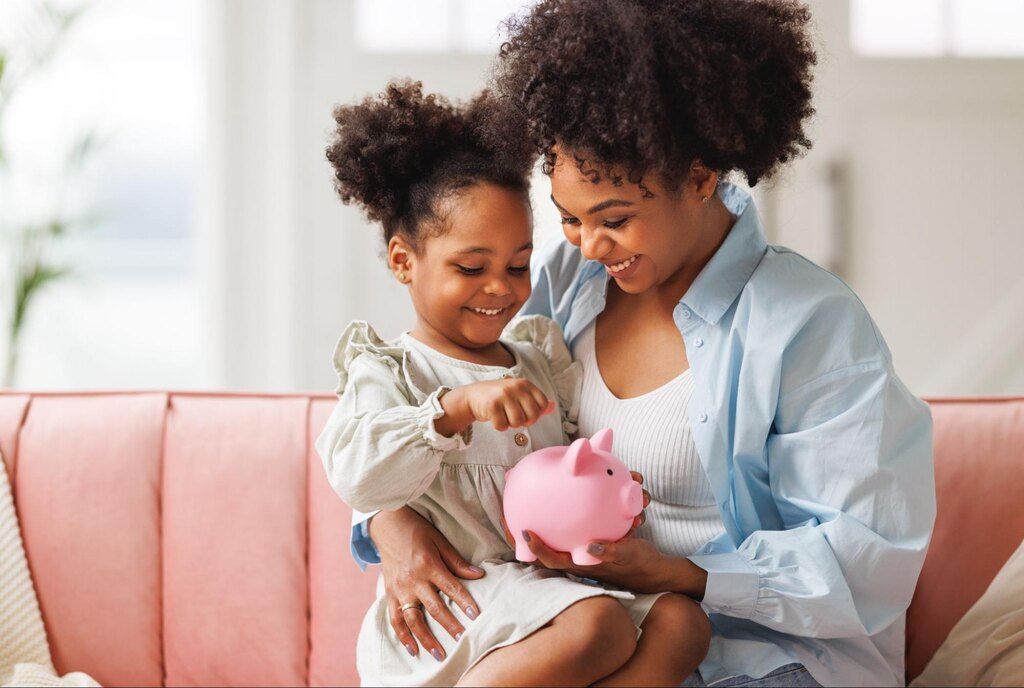 mãe usando cofrinho para ensinar educação financeira infantil para filha