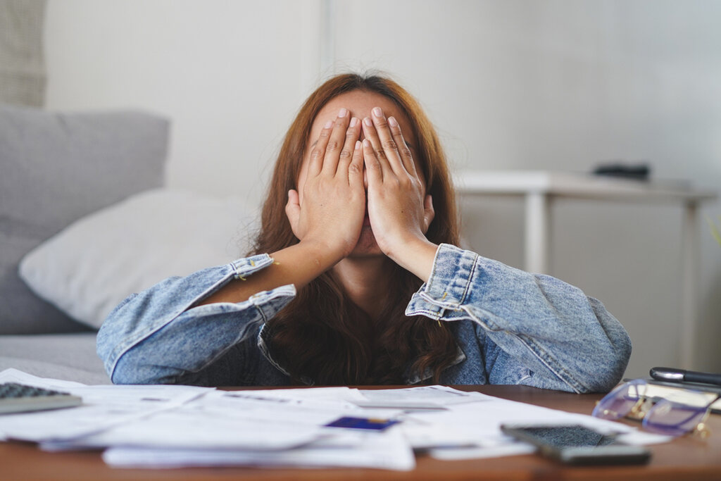 jovem em mesa de escritório preocupada com as finanças, representando a importância da educação financeira para jovens