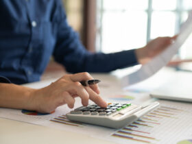 Pessoa usando calculadora e gráficos financeiros como ferramentas para controlar gastos.