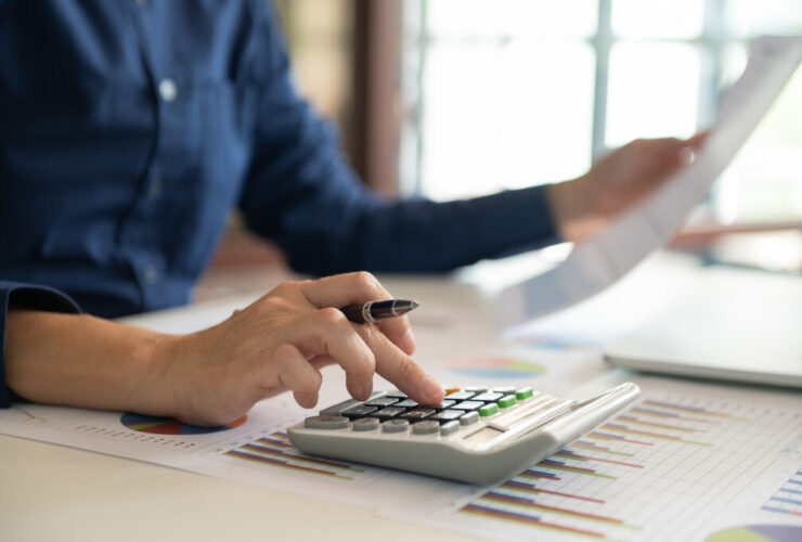 Ferramentas para controlar gastos: como unir inteligência artificial e apps financeiros para economizar de verdade 9 Pessoa usando calculadora e gráficos financeiros como ferramentas para controlar gastos.