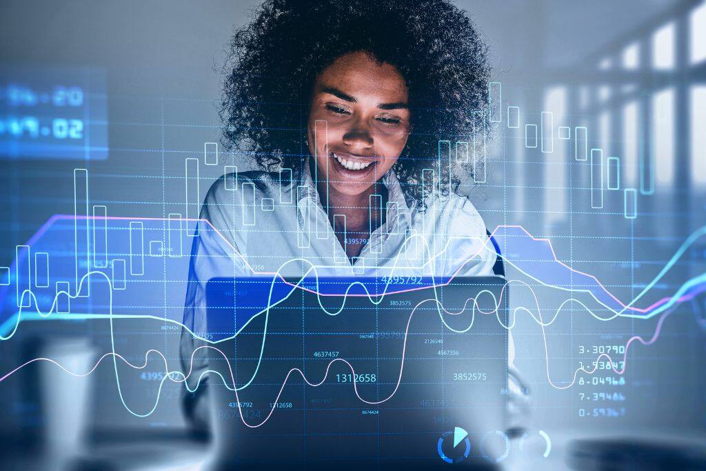 Mulher analisa investimentos com gráficos digitais ao fundo, representando o uso de investimento automatizado por pessoas físicas.