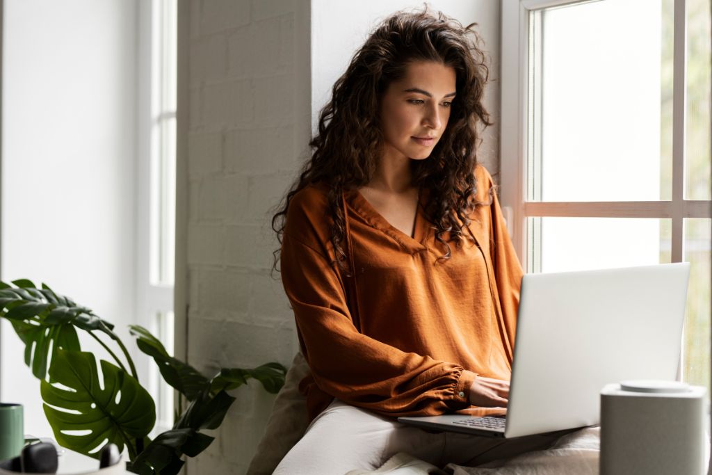 mulher pesquisando no notebook sobre investimentos de baixo risco