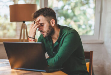 homem preocupado em frente ao notebook representando o que é negativado