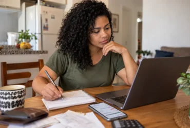 Mulher organizando contas no notebook para fazer uma projeção financeira do orçamento pessoal.