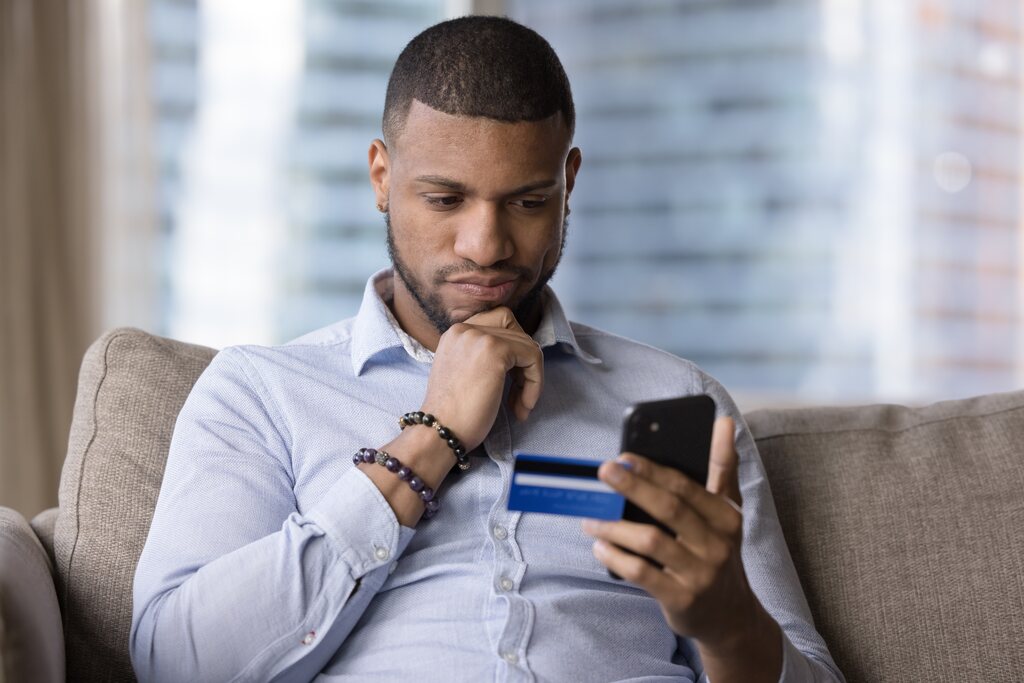 homem mexendo no celular, analisando qual banco digital rende mais
