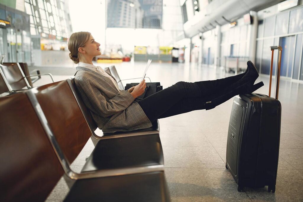 passageira sentado em banco de aeroporto aguardando sua viagem, depois de saber se vale a pena comprar milhas