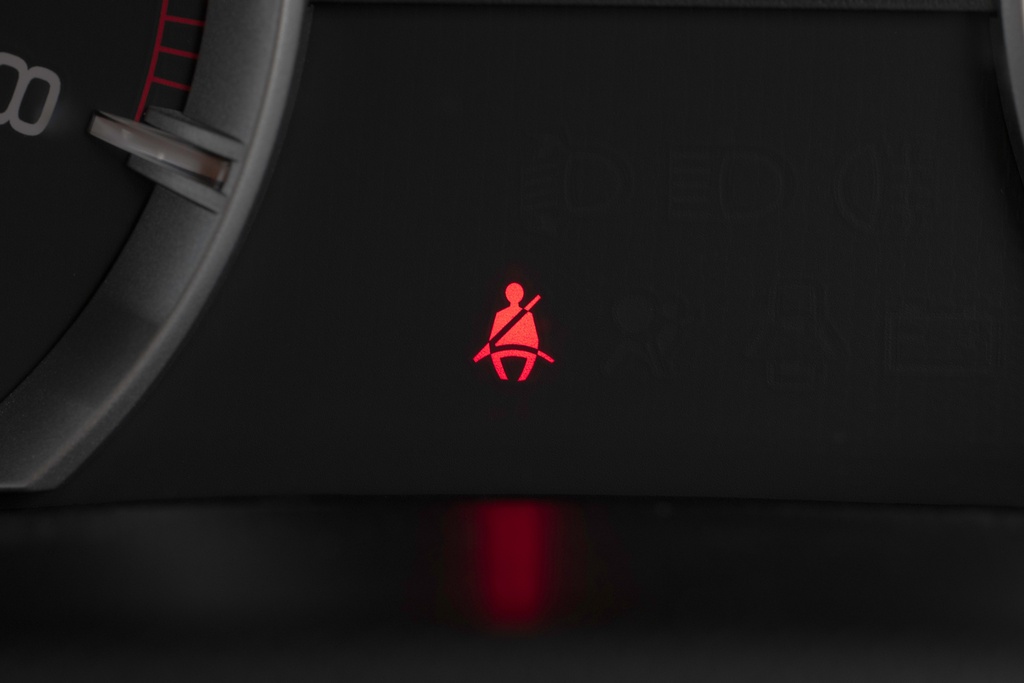Luz de alerta do cinto de segurança no painel do carro, lembrando a importância de proteção e dos tipos de seguros automotivos.