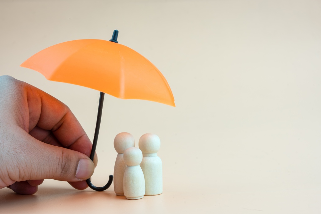 Mão segurando guarda-chuva laranja sobre figuras de família, simbolizando os tipos de seguros que oferecem proteção financeira e pessoal.
